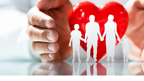 Silhouettes d’une famille découpées en blanc devant un cœur rouge tenu par une main, symbolisant la protection, la santé et le bien-être familial.